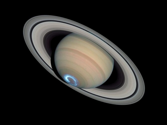 Это комбинация из трех последовательных фотографий. Астрономы объединили ультрафиолетовые кадры южного полярного региона Сатурна с видимым светом планеты и ее кольцами, чтобы воссоздать это невероятное зрелище. Авроральная зона (сияние) покажется красной, если наблюдать ее на Сатурне. Так происходит из-за наличия водорода в атмосфере. На Земле заряженные солнечным светом частицы контактируют с азотом и кислородом в верхних слоях, создавая цветные сияния зеленого и синего цветов.